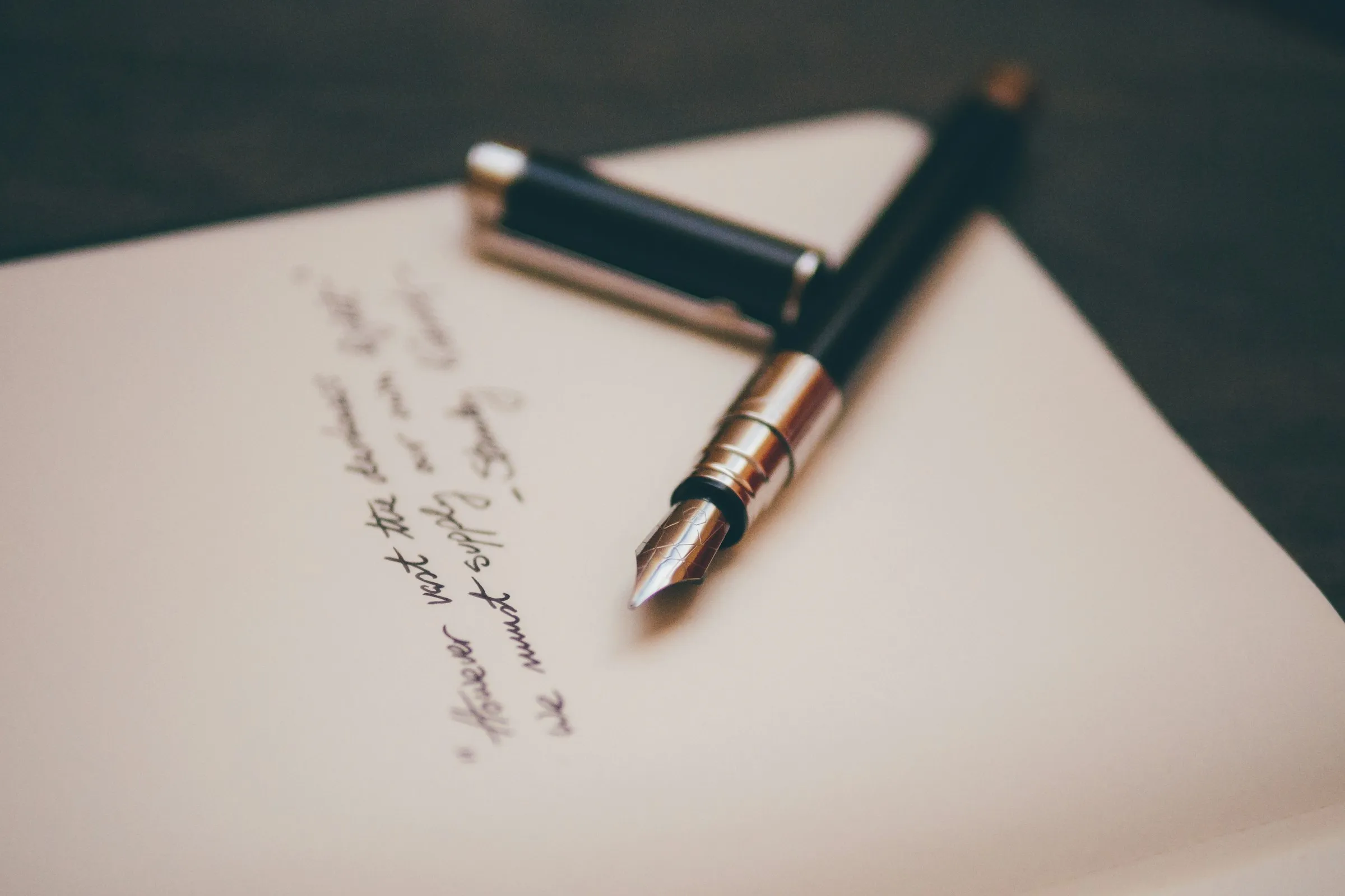A fountain pen resting on cream stationery, mid-letter